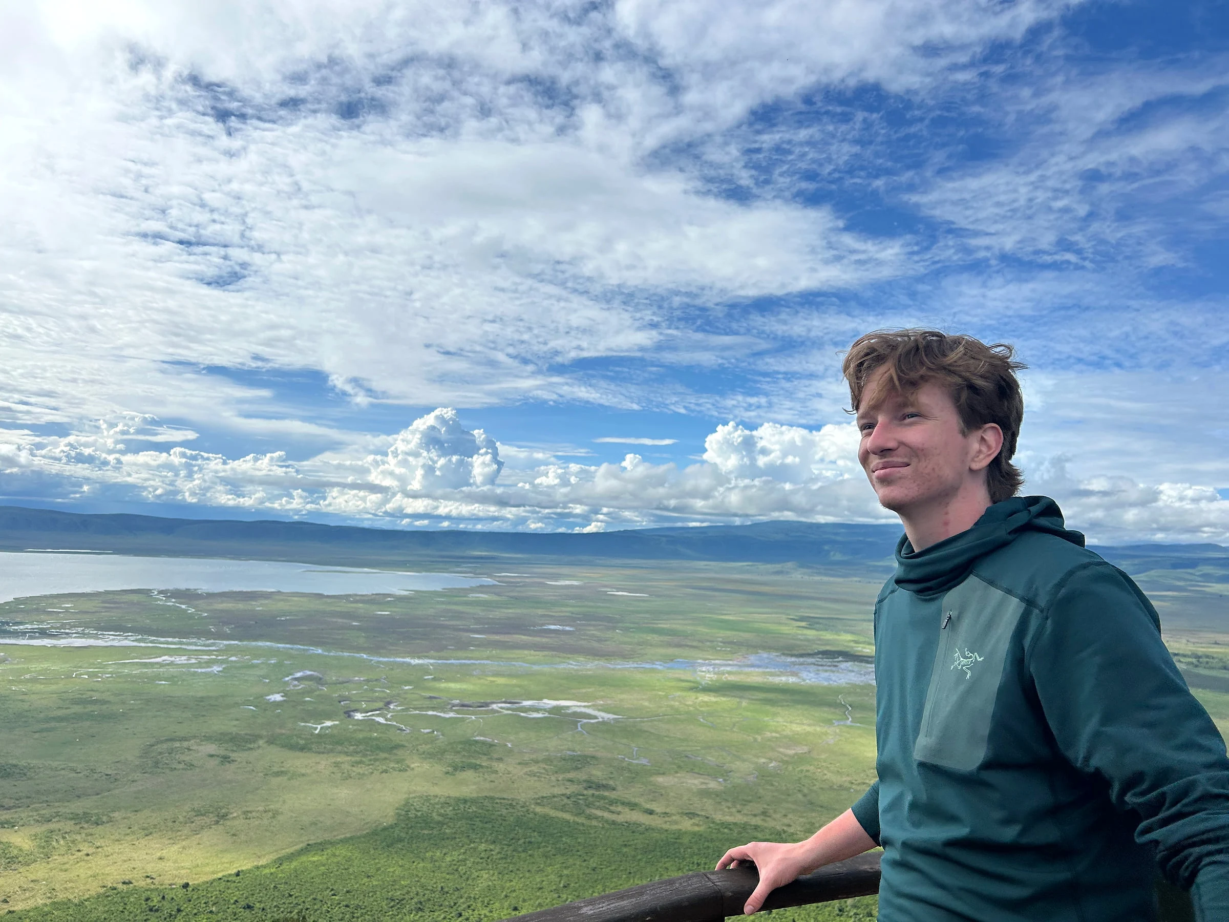 Ethan stands at an overlook above a broad wetland beneath a dramatic blue sky.