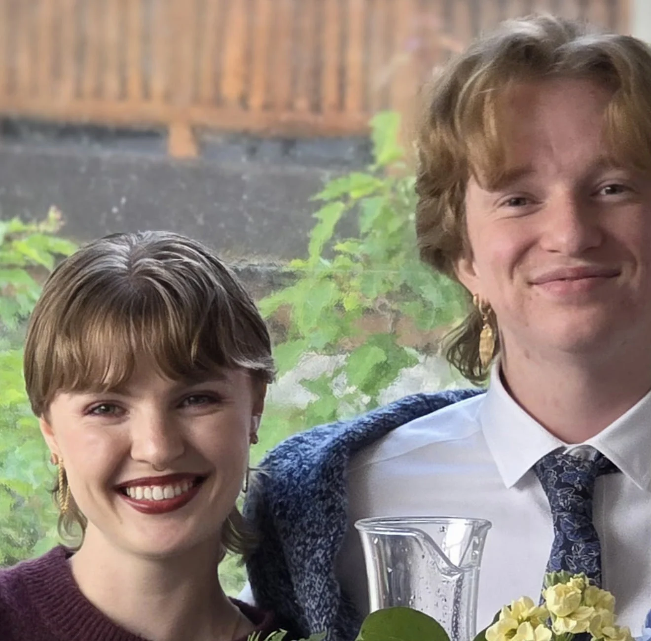 A smiling couple poses together at a table decorated with flowers.